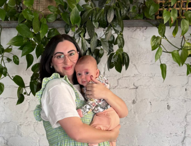 Woman holding baby and smiling.
