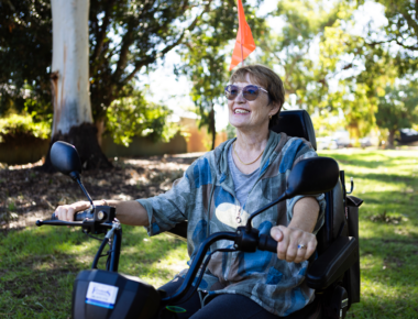 women outdoors on mobility scooter smiling
