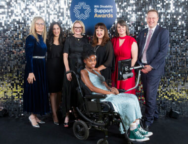 A group of people posing with their award against a sparkly backdrop