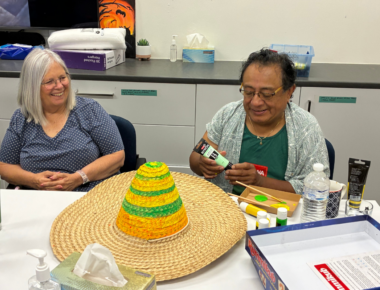 Two people sat next to each other to create arts and craft.