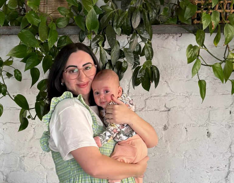 Woman holding baby and smiling.