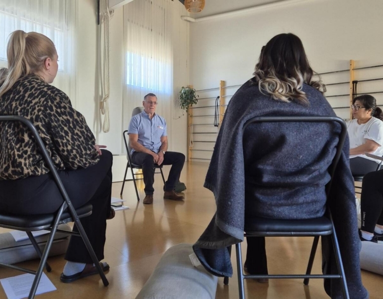 Two women sit next to each other on a chair.