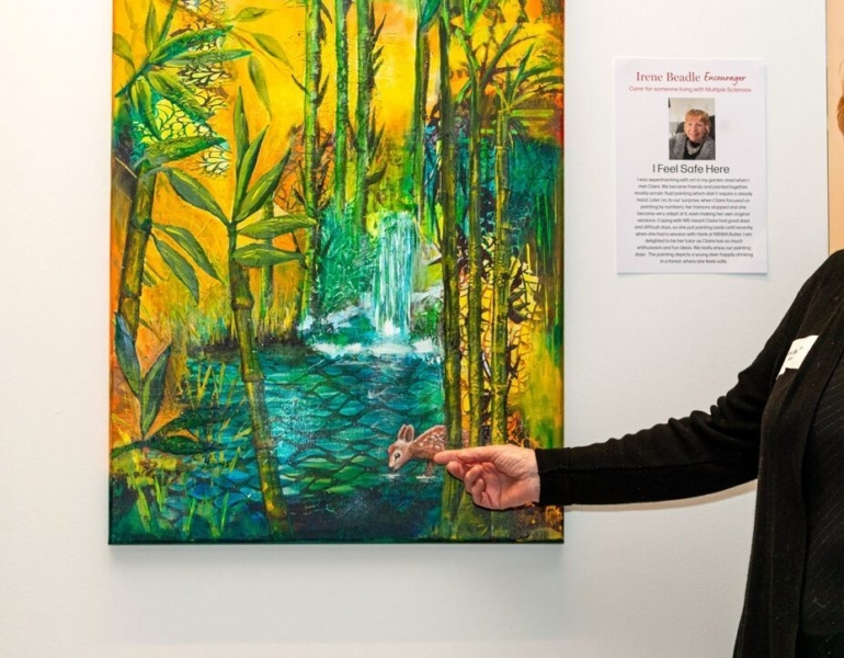 artist posing next to artwork