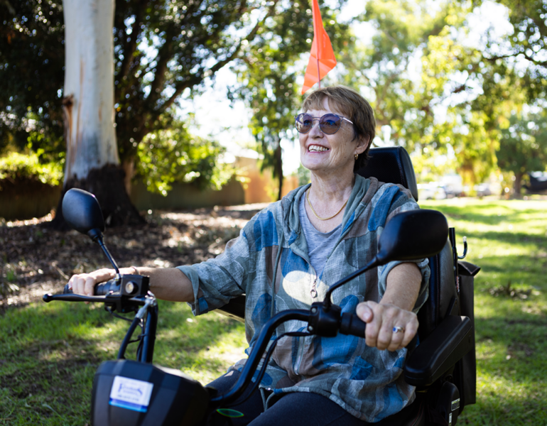 women outdoors on mobility scooter smiling