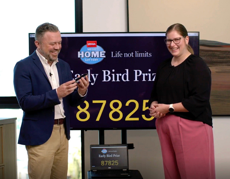 Two people stand in front of a screen making a phone call