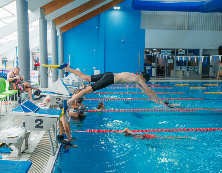 man diving into indoor pool