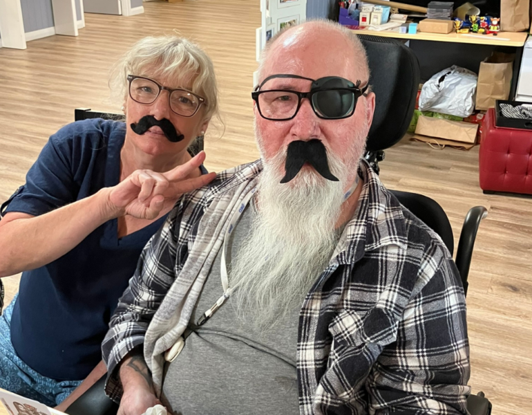 Female and male donning fake moustaches.