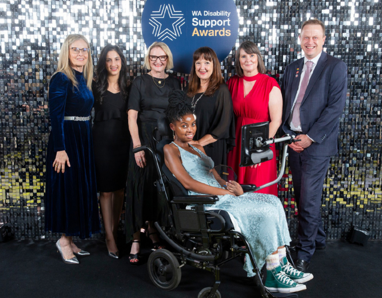 A group of people posing with their award against a sparkly backdrop