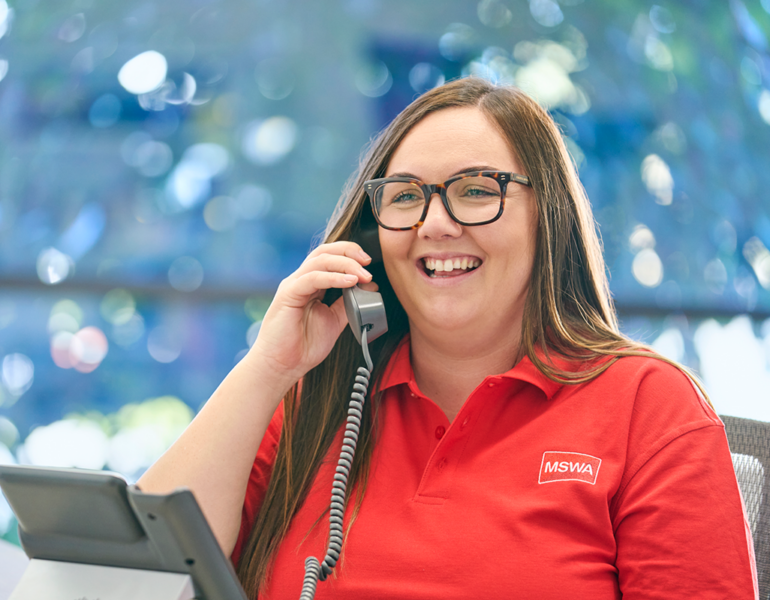 Women wearing a red MSWA shirt and speaking on the phone smiling