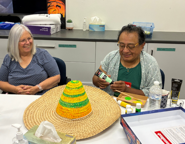 Two people sat next to each other to create arts and craft.