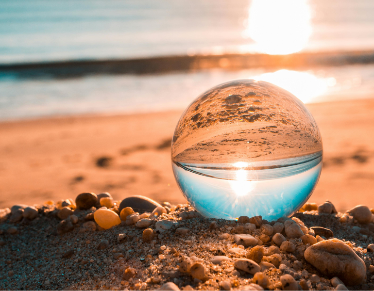Glass ball on a sandy beach at sunrise