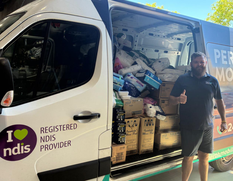 Person standing beside a delivery van filled with donated supplies, giving a thumbs-up