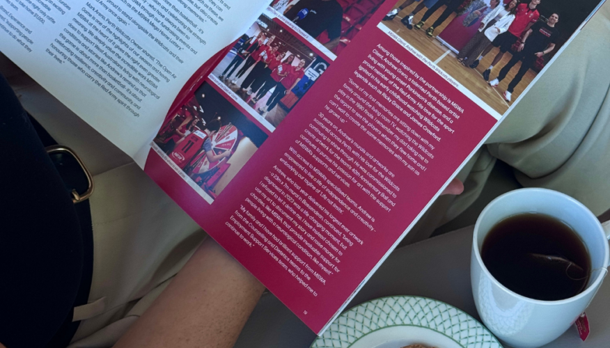 Person holding a magazine with a coffee and tea next to them.