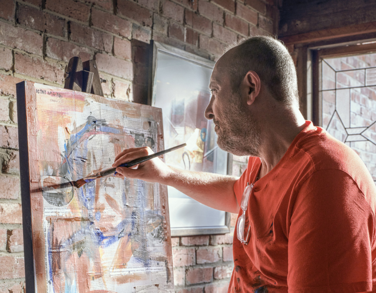 Man holding a brush and painting a canvas
