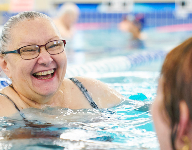 woman smiling and swimming in a pool