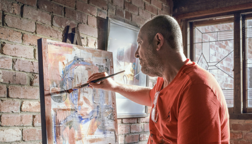 Man holding a brush and painting a canvas