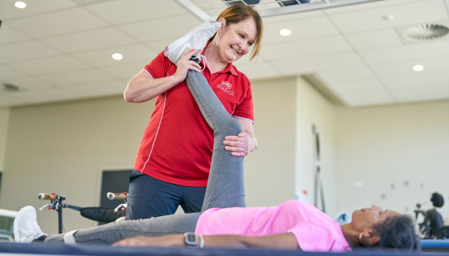 MSWA staff assisting a client with exercises while lying down