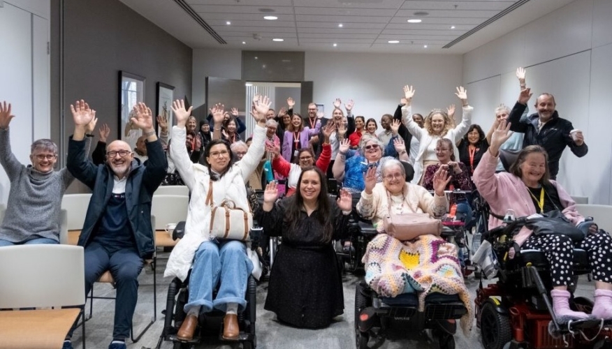 group of people smiling at the camera, raising their hands in celebration