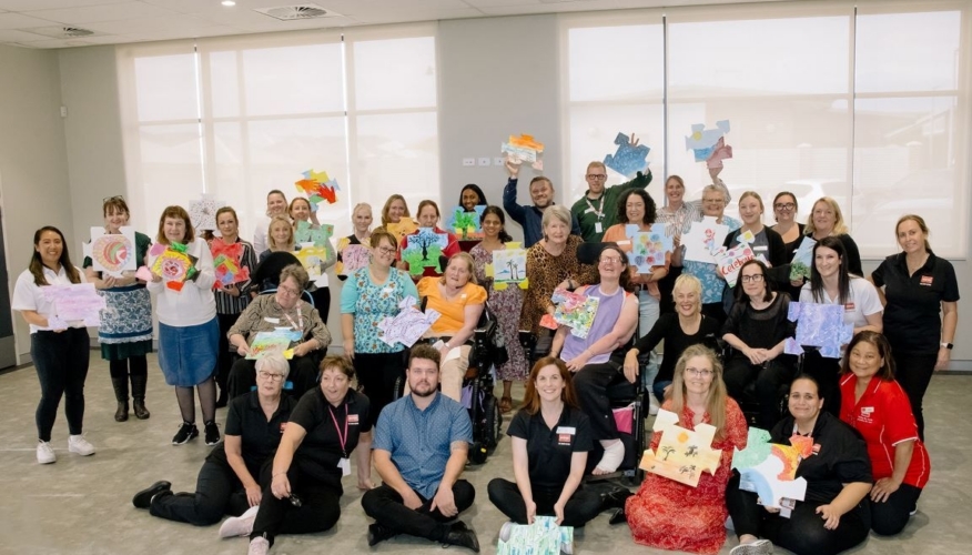 large group of people posting with their artwork