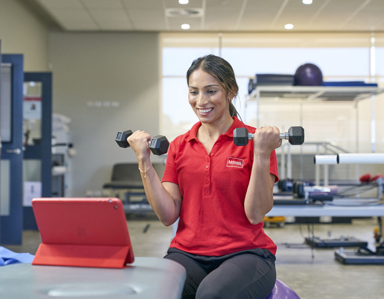 mswa staff member holding weights during a telehealth session