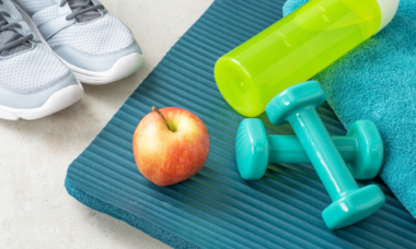 image of weights, water bottle and an apple on a gym mat
