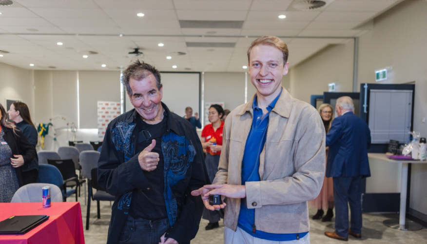 Man holding a device standing next to a man holding a thumbs up.