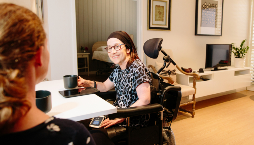 two women speaking and smiling while drinking coffee