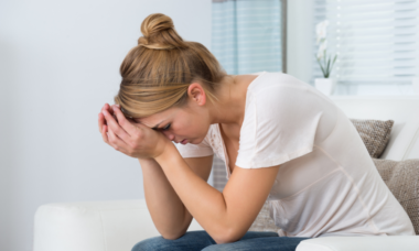 woman crouching and holing her hands on her forehead looking distressed