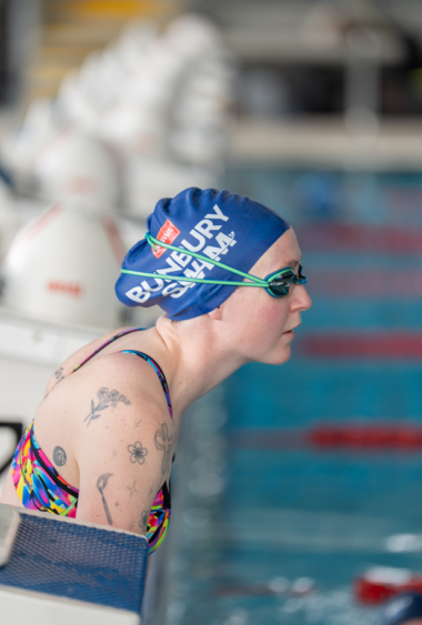 A person wearing a swimming camp about to jump into a pool.