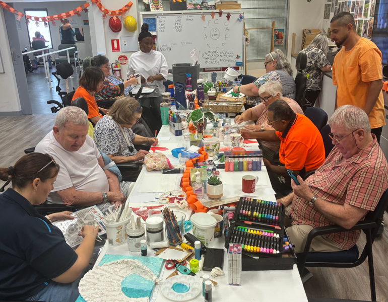 Community members gathered around a table taking part in a group arts and crafts activity