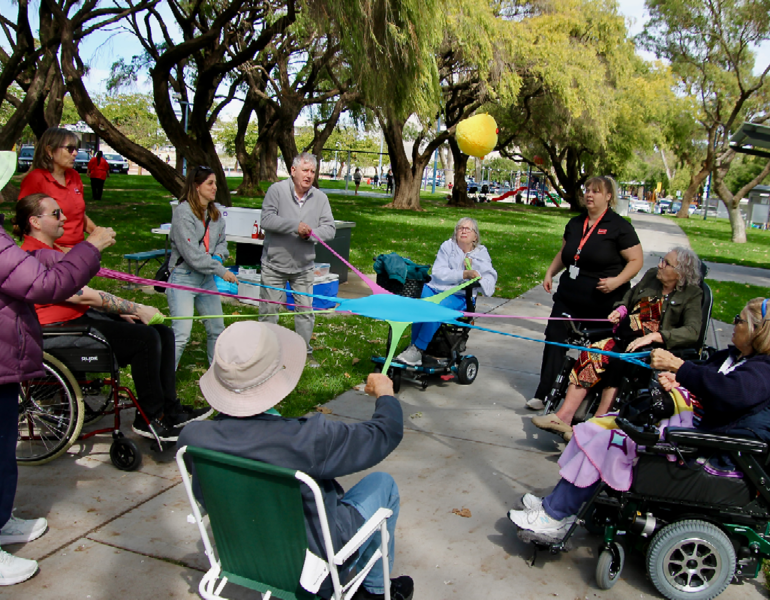Participants and staff enjoying an inclusive outdoor group activity in a park setting