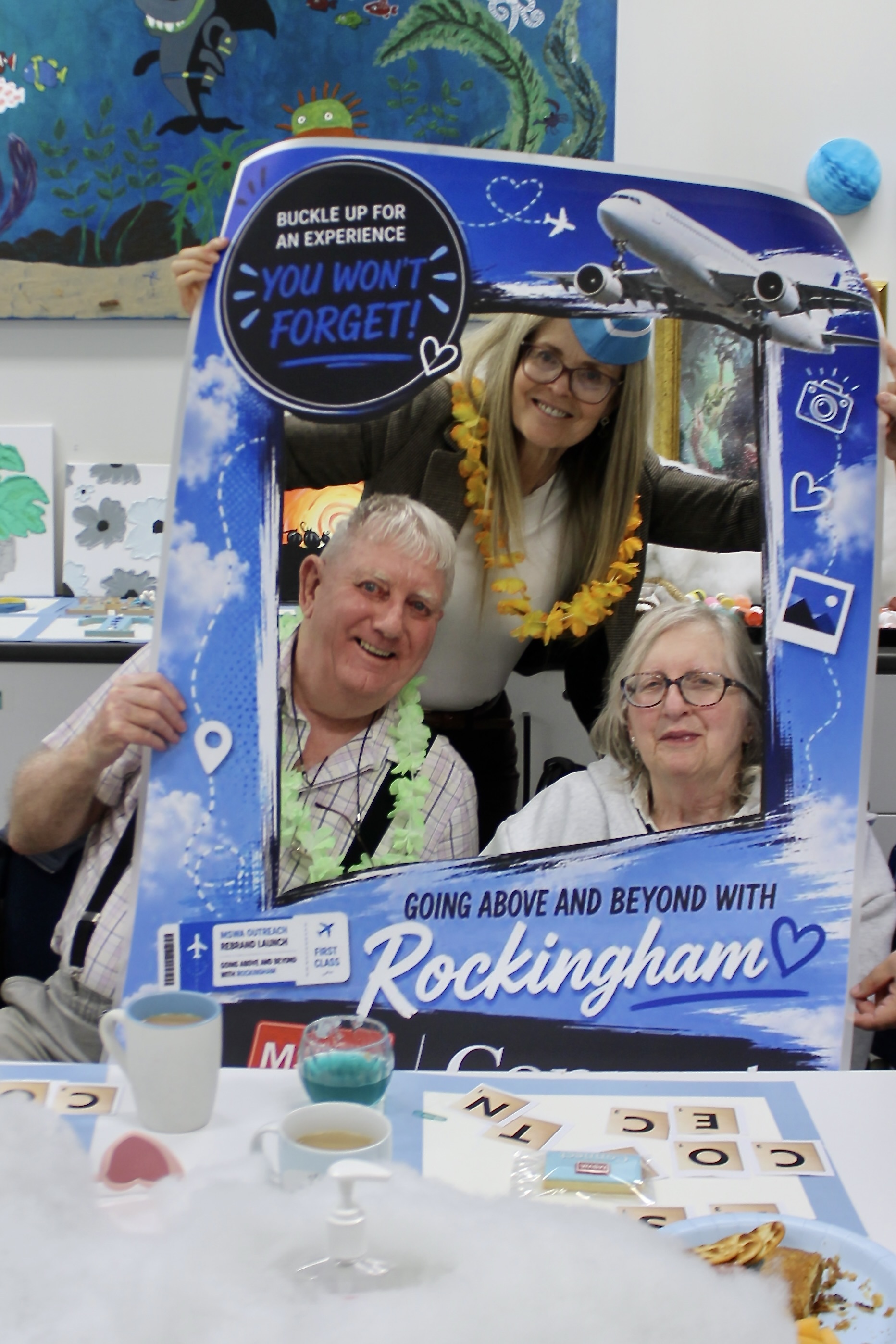 Three people using a frame to take a photo and smiling.